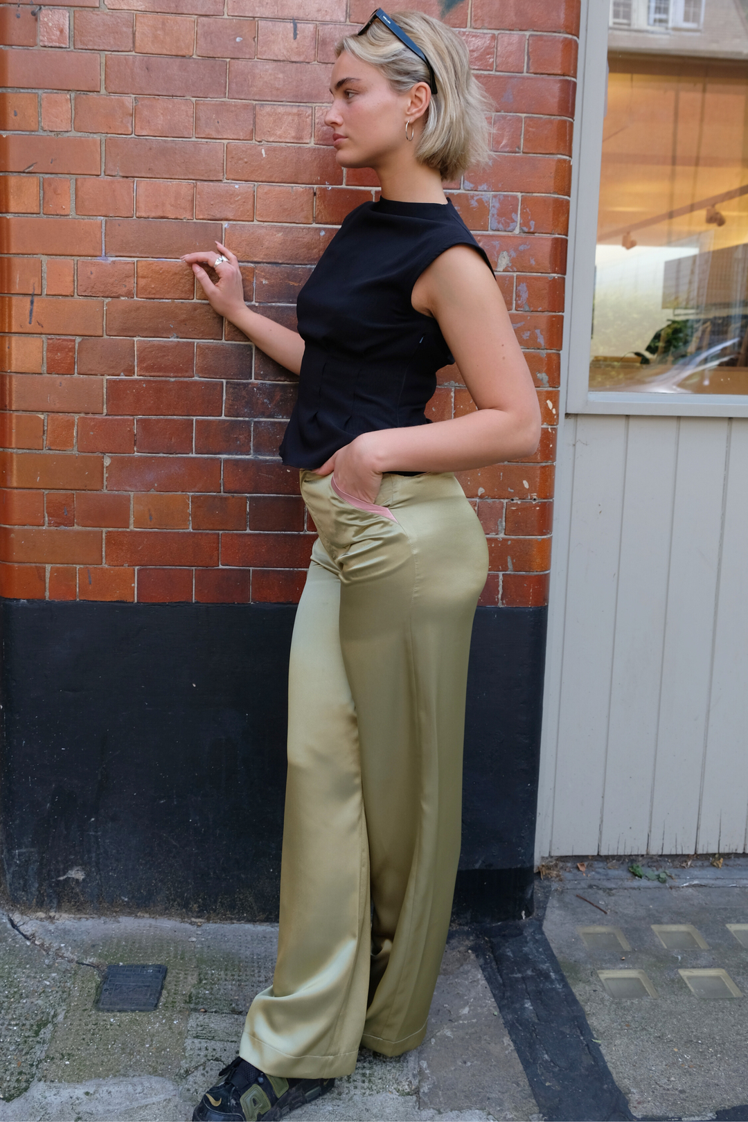 Olive wide-leg silk trousers with pale pink trims, worn in London