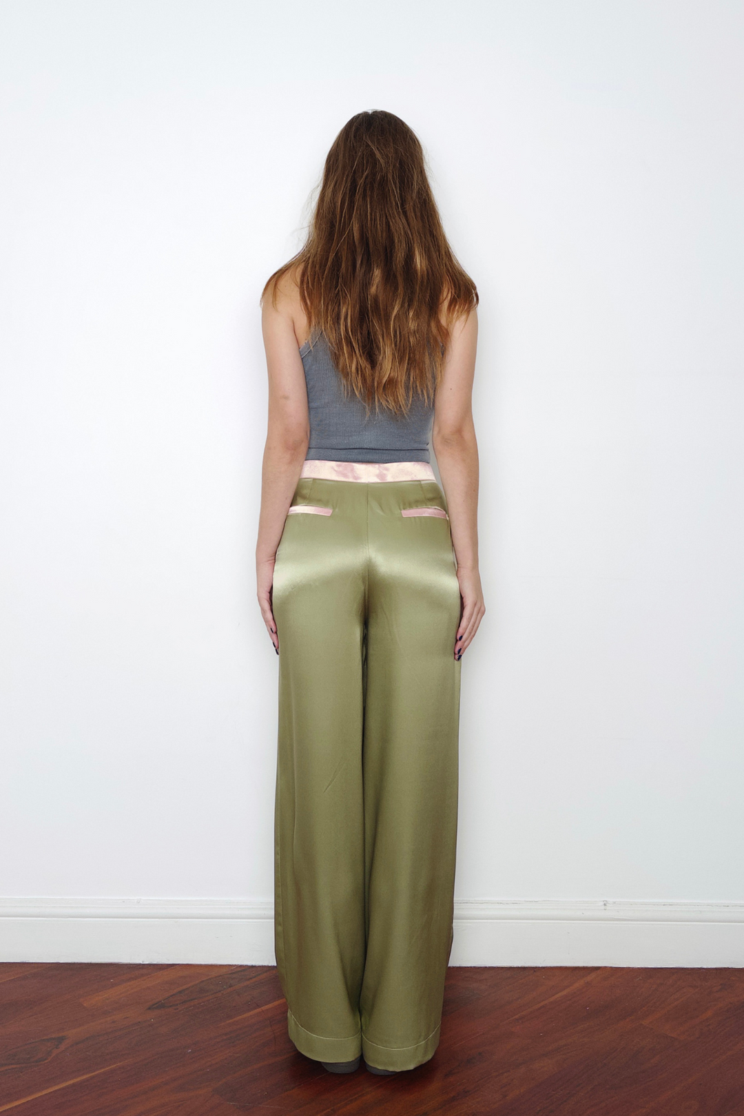 Olive wide-leg silk trousers with pale pink trims, worn in London